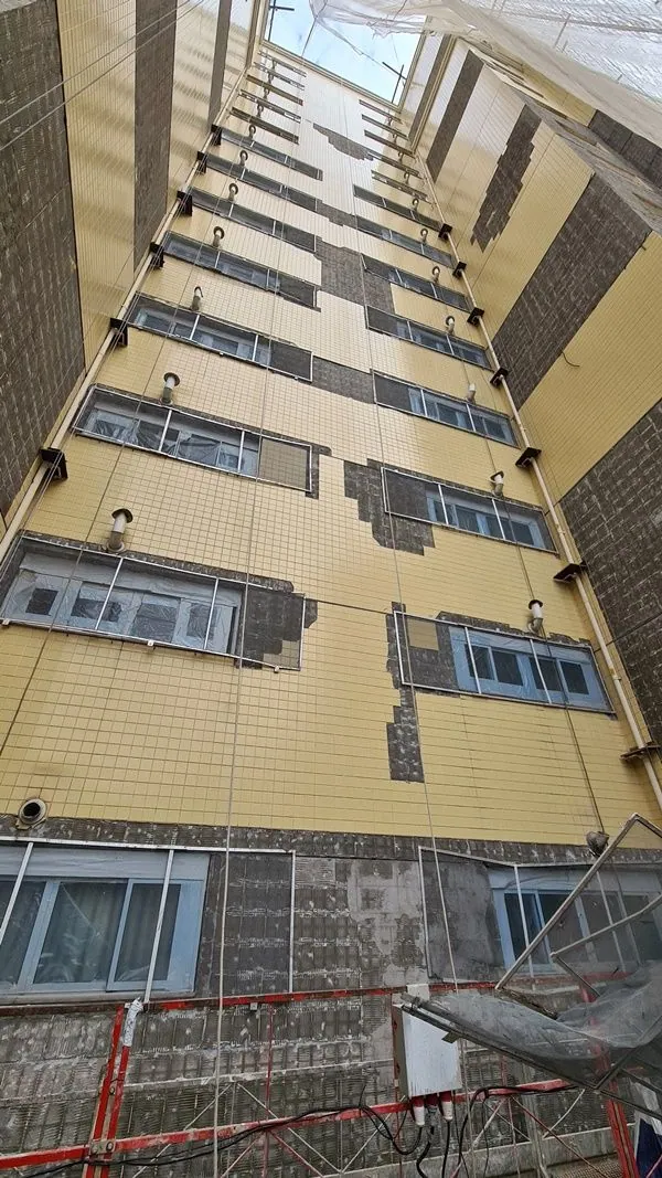 Fachada amarela em obra de recuperação com telas de proteção